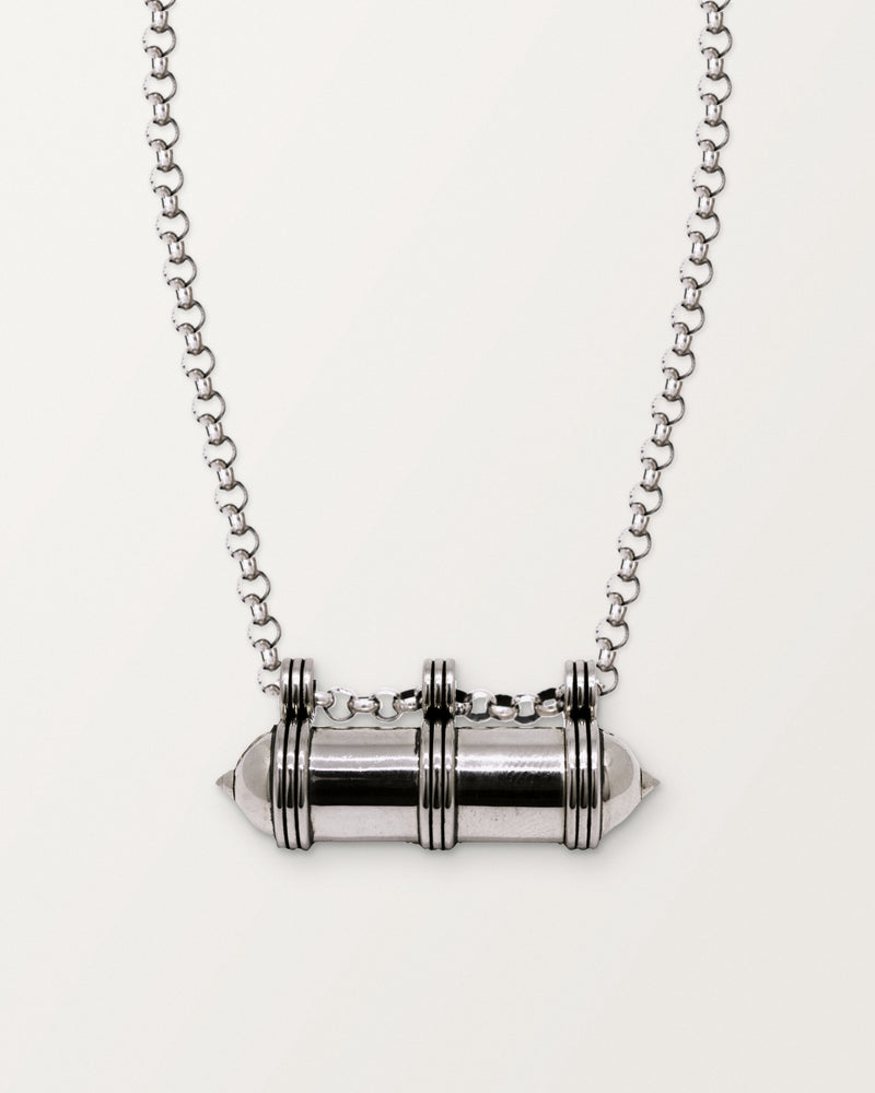 Sterling silver Pankaj amulet necklace, closed, on a warm bone-white background, chain exiting the top of frame.