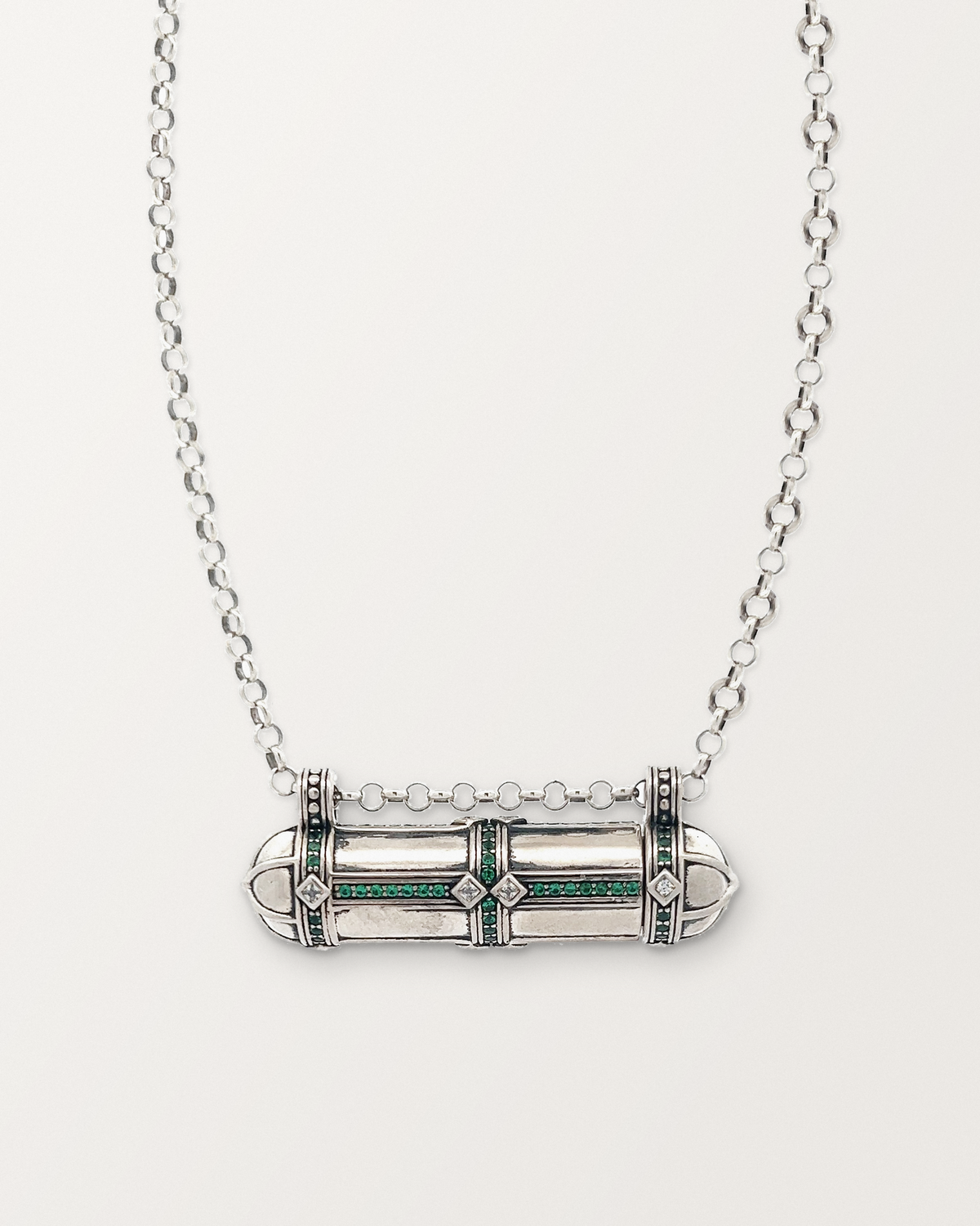 Sterling silver Afghani Tribal Emerald amulet necklace, closed, on a warm bone-white background.