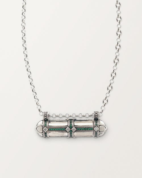 Sterling silver Afghani Tribal Emerald amulet necklace, closed, on a warm bone-white background.
