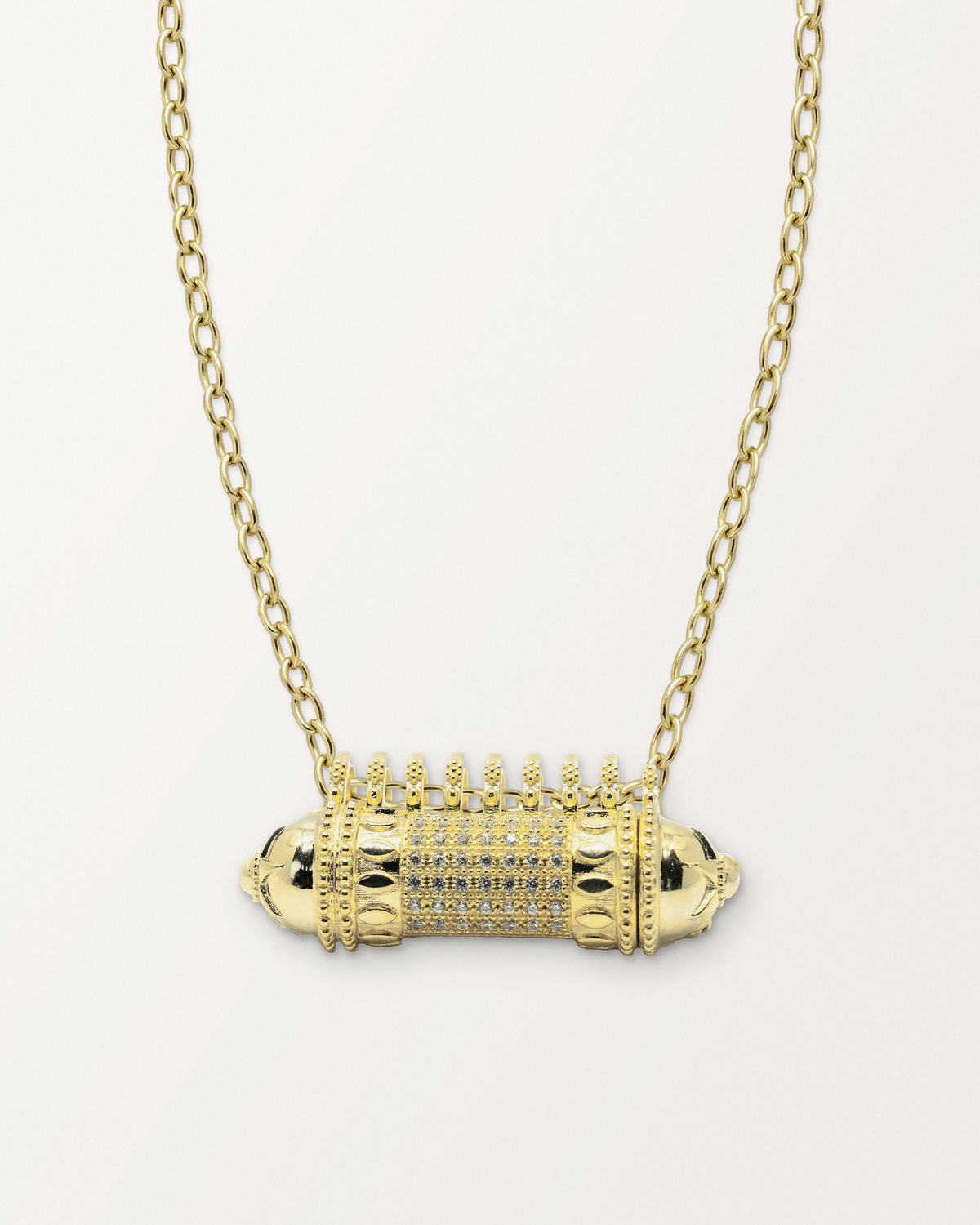 Antique Pave openable amulet necklace in 14K or 18K yellow gold, closed, on a warm bone-white background.