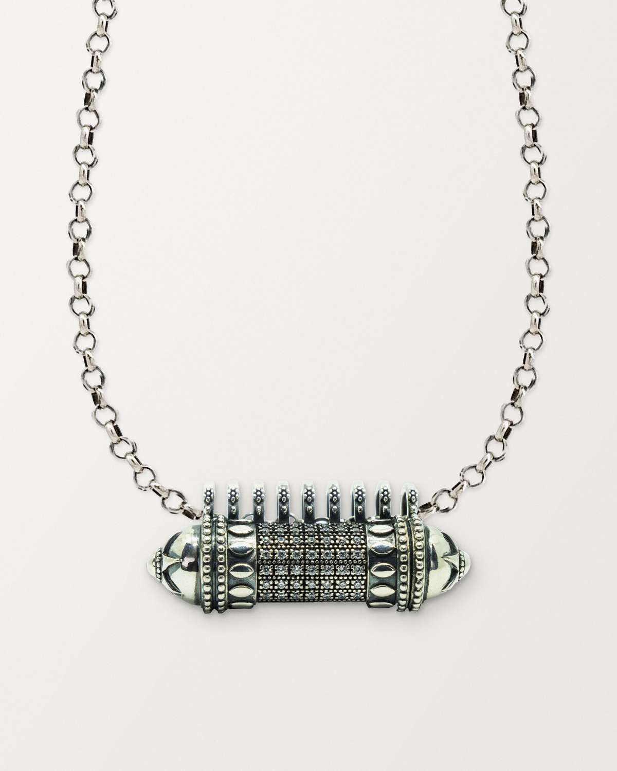 Sterling silver Antique Pave amulet necklace, closed, on a warm bone-white background, chain exiting the top of frame.