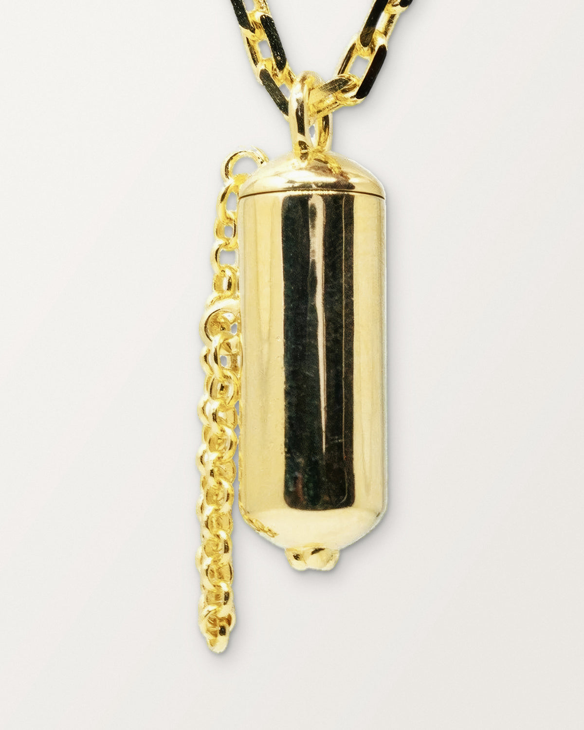 Close-up of the Capsule Small openable amulet necklace in 14K or 18K yellow gold, closed, front, on a warm bone-white background.