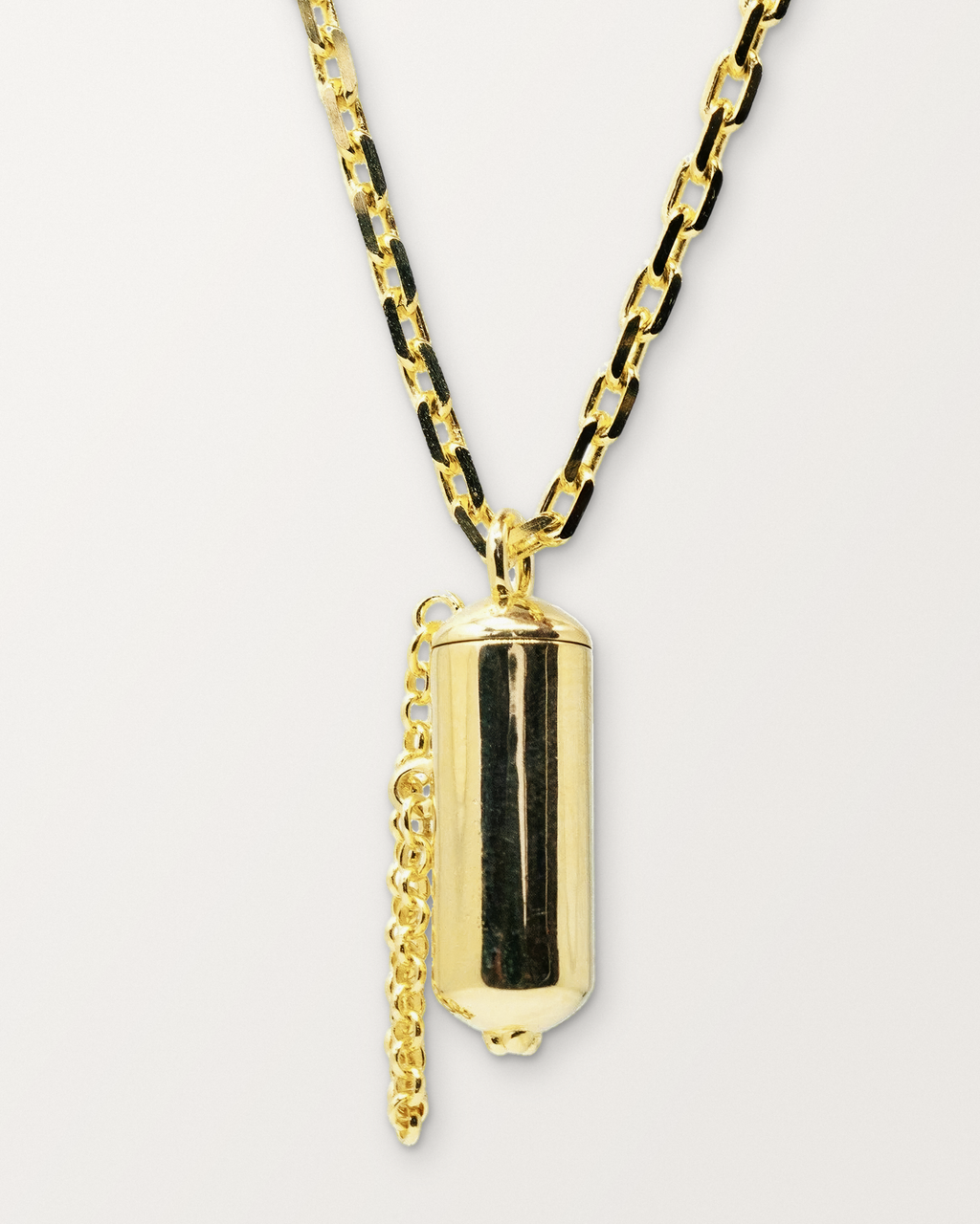 Capsule Small openable amulet necklace in 14K or 18K yellow gold, shown closed on a warm bone-white background.