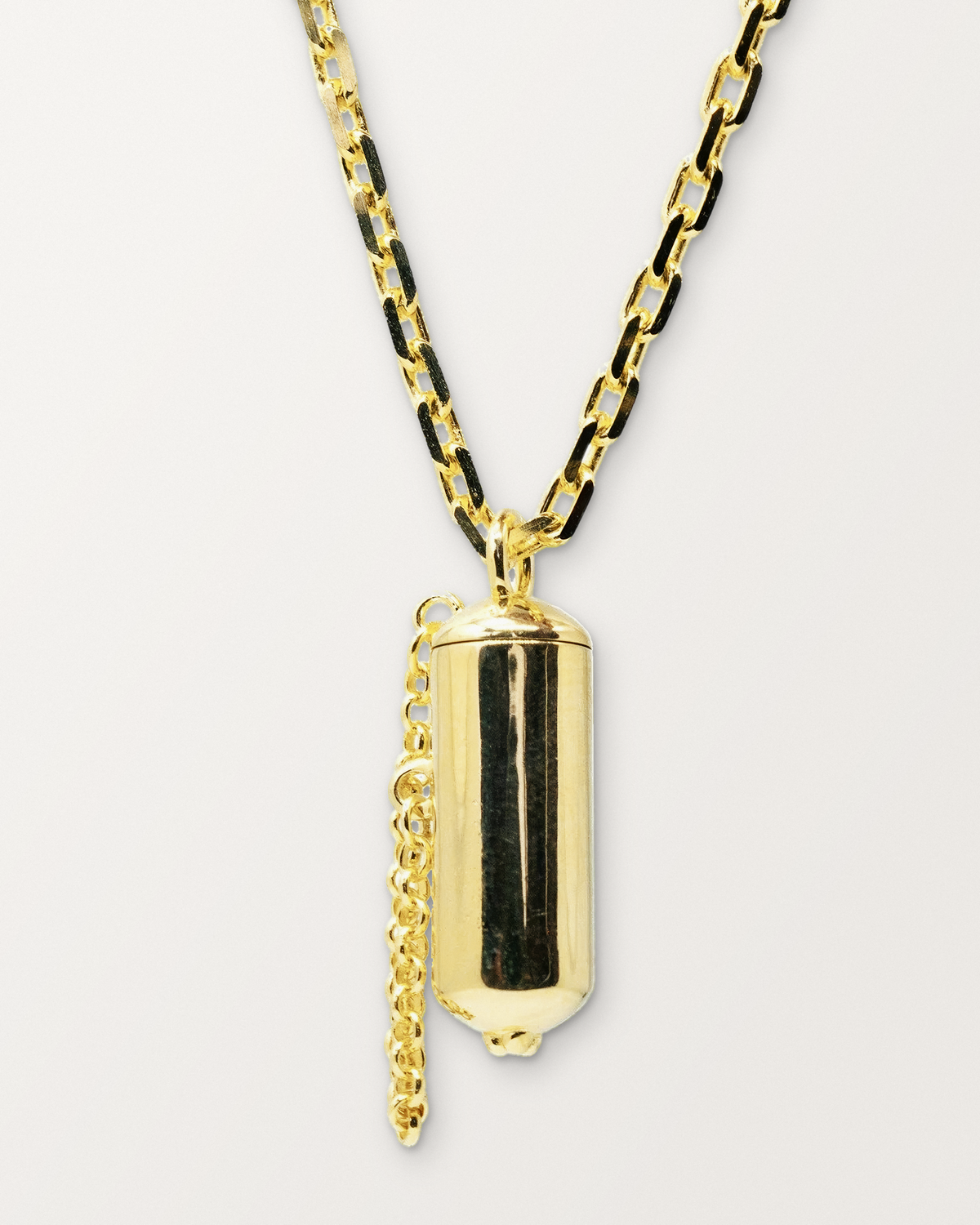 Capsule Small openable amulet necklace in 14K or 18K yellow gold, shown closed on a warm bone-white background.