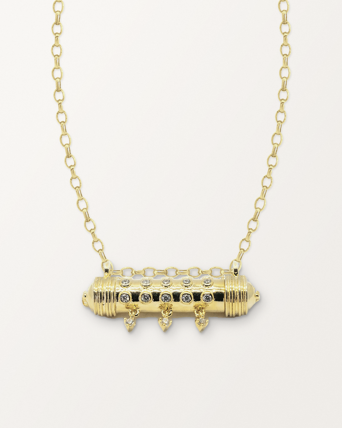 Hirz openable amulet necklace in 14K or 18K yellow gold, closed, on a warm bone-white background.