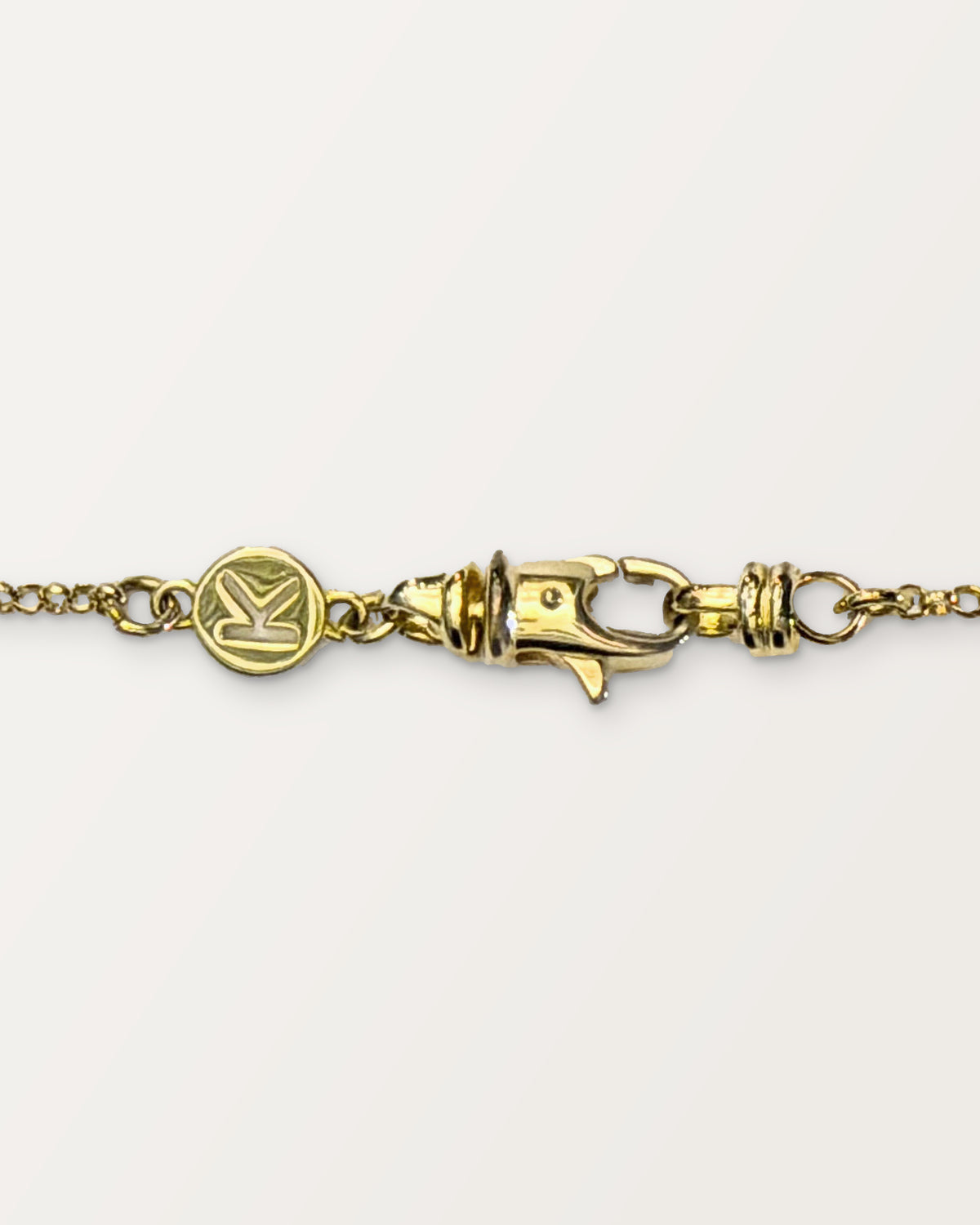 The small Kavacha clasp with its branded K tag, in 14K or 18K yellow gold.