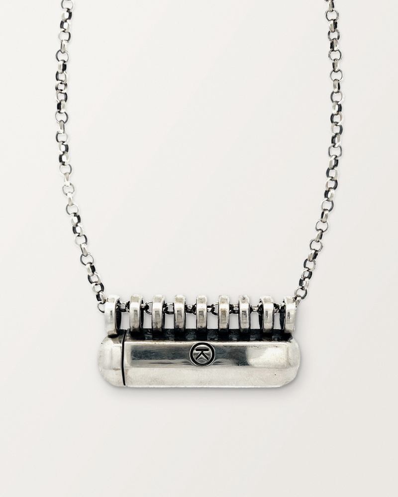 Sterling silver Kerala Large amulet necklace, closed, on a warm bone-white background, chain exiting the top of frame.