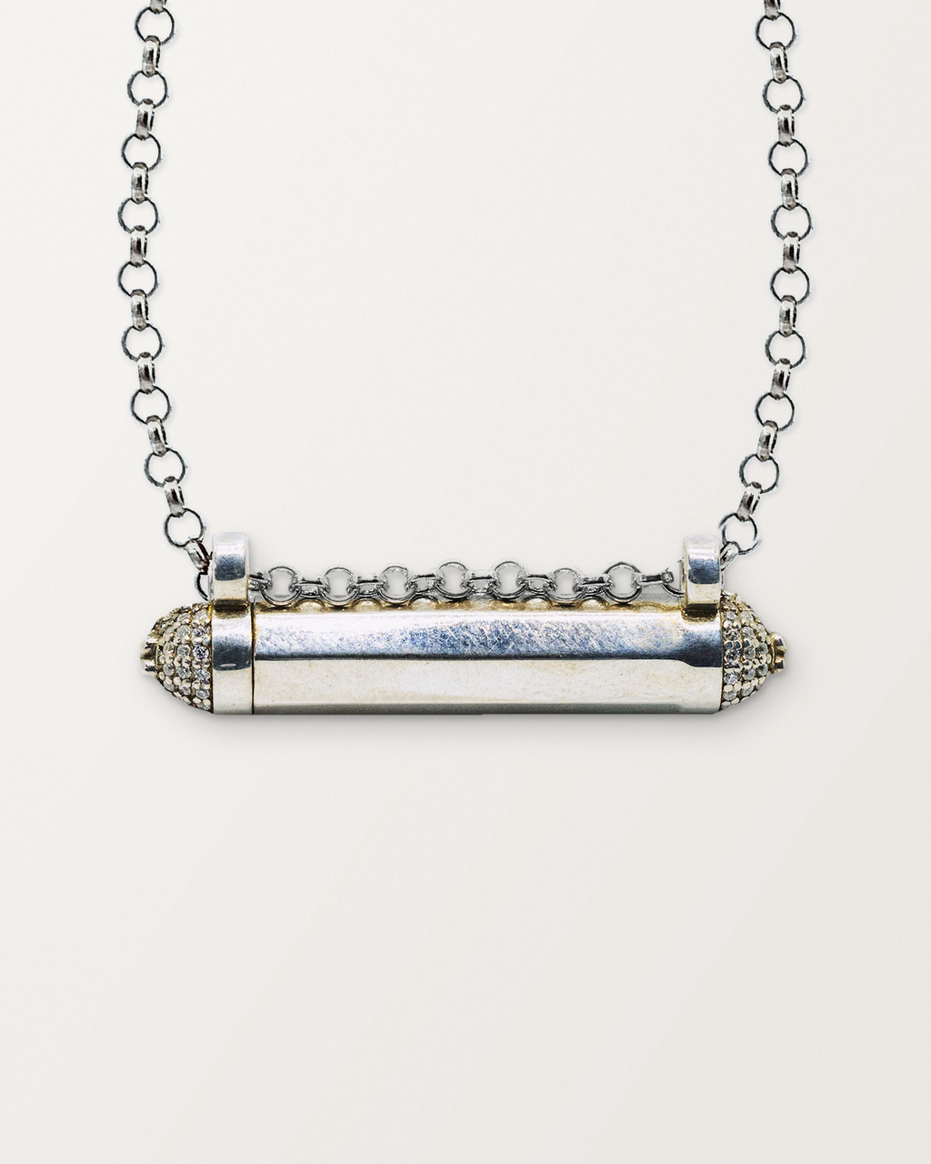 Close-up of the closed sterling silver Kerala Pave amulet necklace, front, on a warm bone-white background.