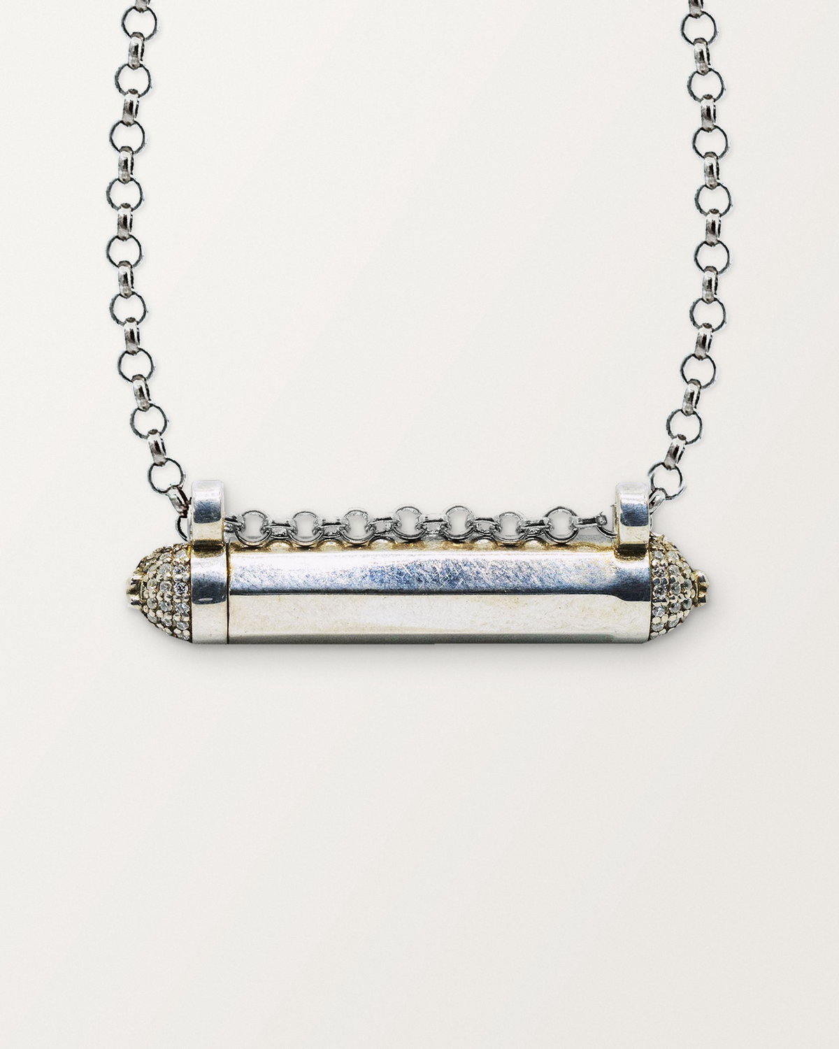 Close-up of the closed sterling silver Kerala Pave amulet necklace, front, on a warm bone-white background.