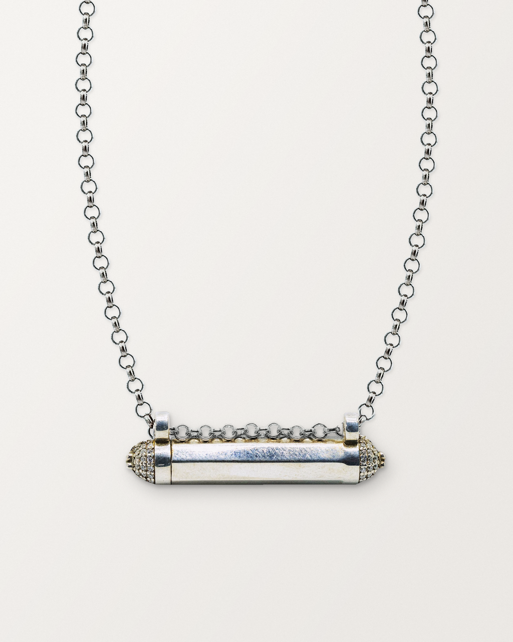 Sterling silver Kerala Pave amulet necklace, closed, on a warm bone-white background, chain exiting the top of frame.