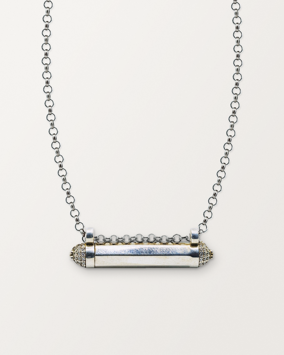 Sterling silver Kerala Pave amulet necklace, closed, on a warm bone-white background, chain exiting the top of frame.
