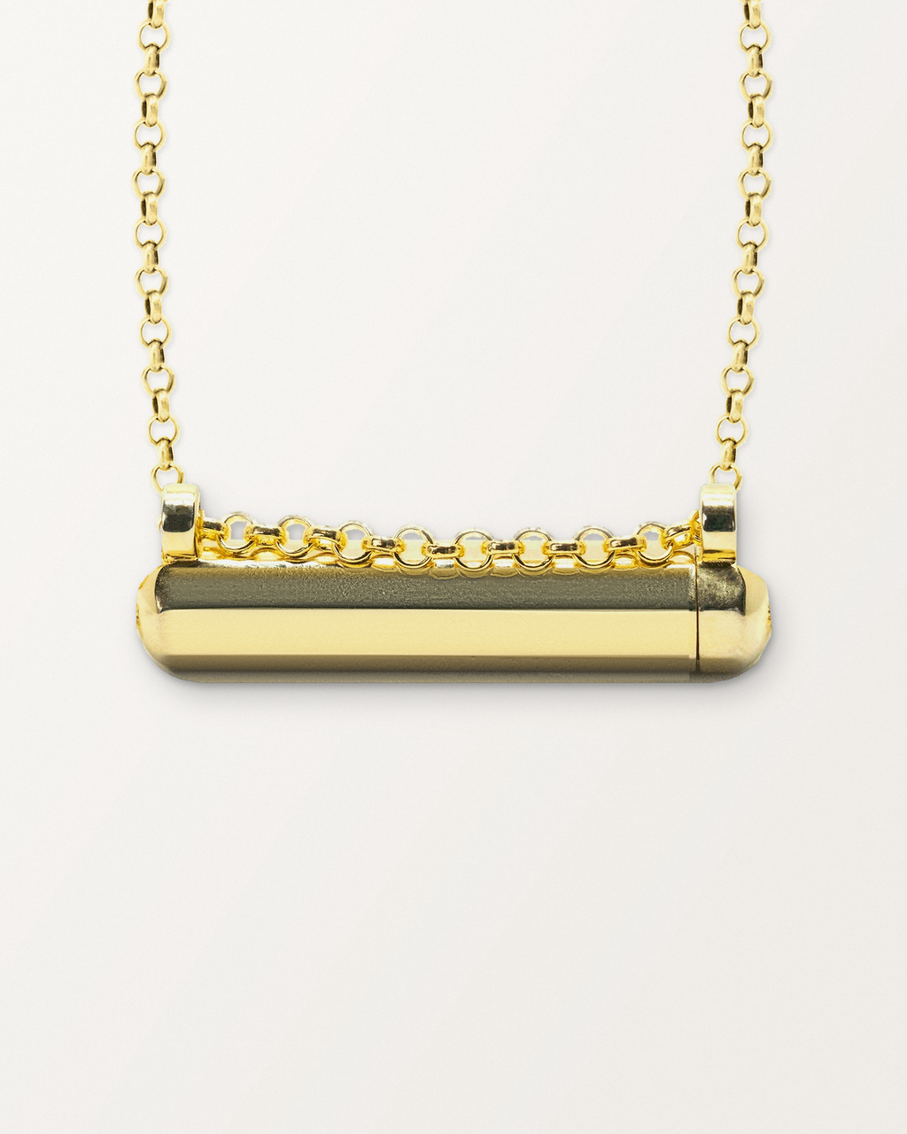 Close-up of the Kerala Small openable amulet necklace in 14K or 18K yellow gold, closed, front, on a warm bone-white background.