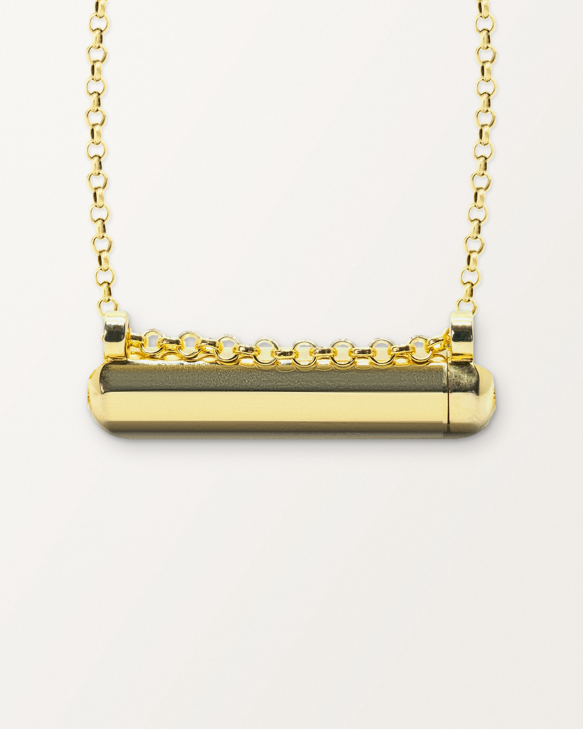 Close-up of the Kerala Small openable amulet necklace in 14K or 18K yellow gold, closed, front, on a warm bone-white background.