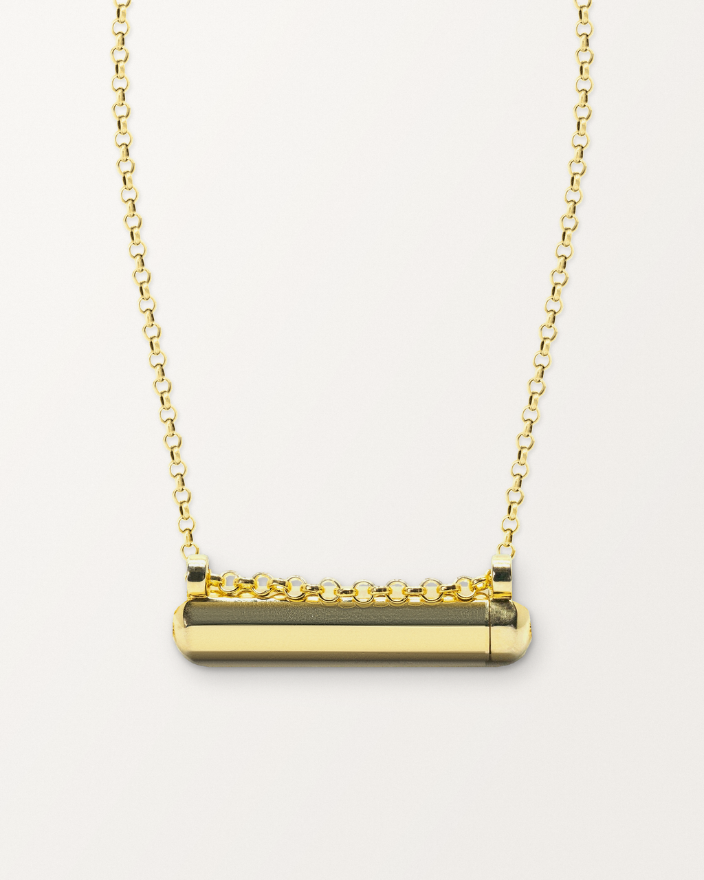 Kerala Small openable amulet necklace in 14K or 18K yellow gold, shown closed on a warm bone-white background.