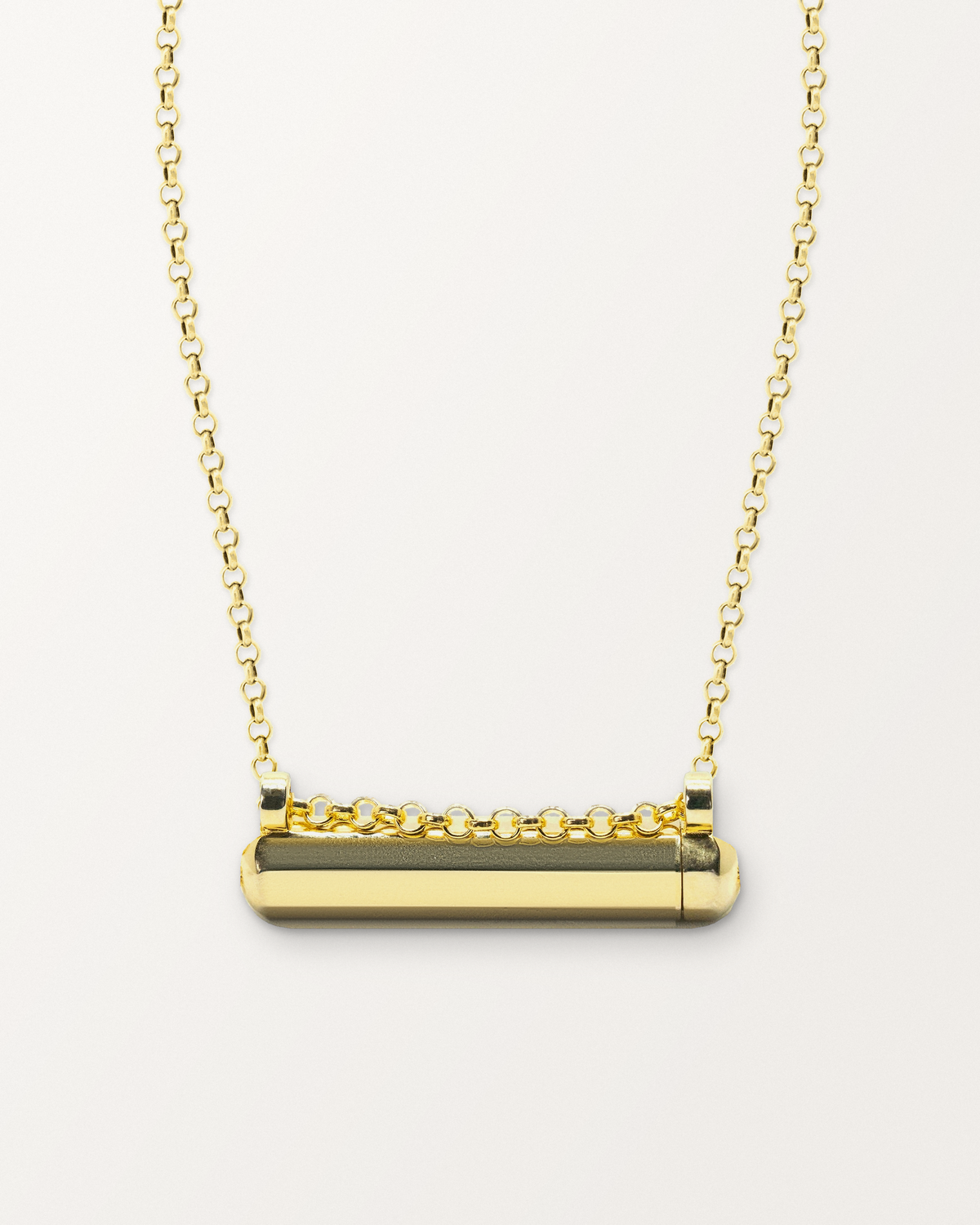 Kerala Small openable amulet necklace in 14K or 18K yellow gold, shown closed on a warm bone-white background.