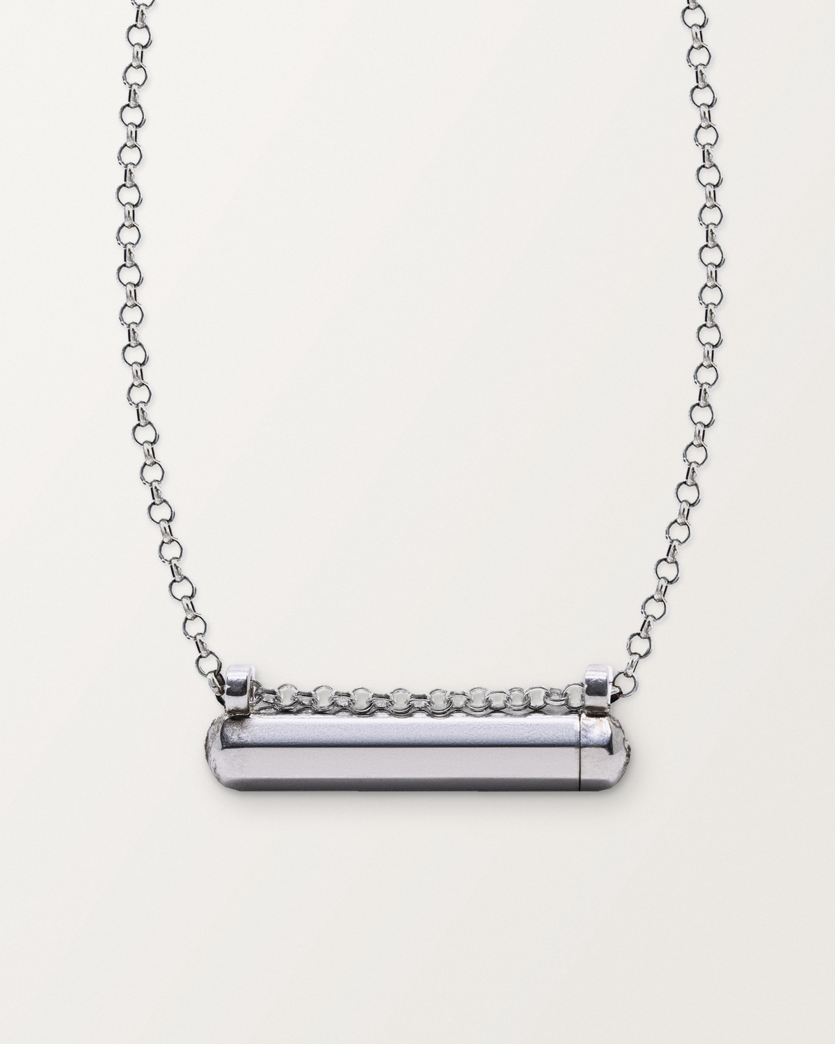 Sterling silver Kerala Small amulet necklace, closed, on a warm bone-white background, chain exiting the top of frame.