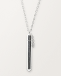 Sterling silver Moksha amulet necklace, closed, hanging on its chain against a warm bone-white background.