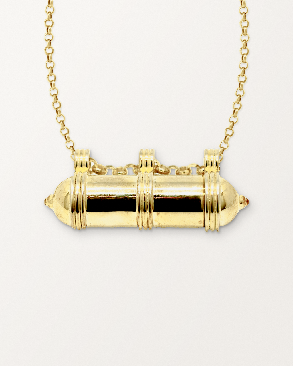 Close-up of the Pankaj openable amulet necklace in 14K or 18K yellow gold, closed, front, on a warm bone-white background.