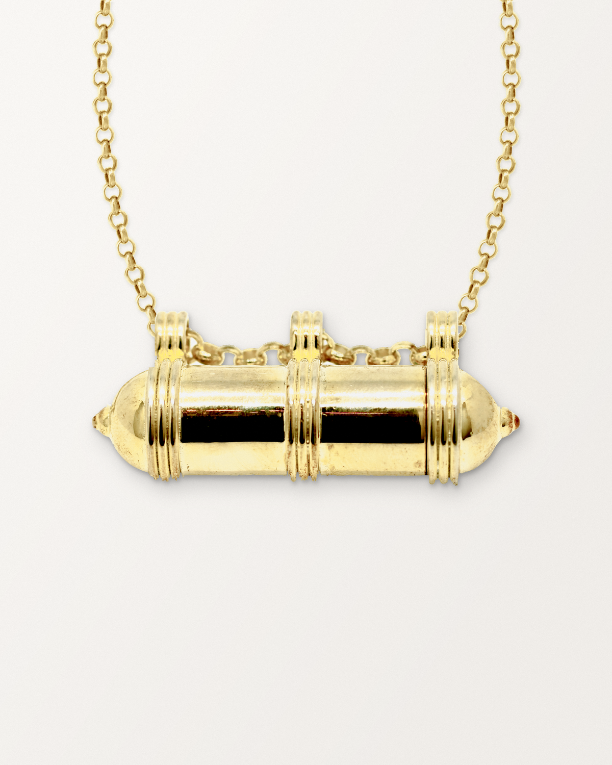 Close-up of the Pankaj openable amulet necklace in 14K or 18K yellow gold, closed, front, on a warm bone-white background.