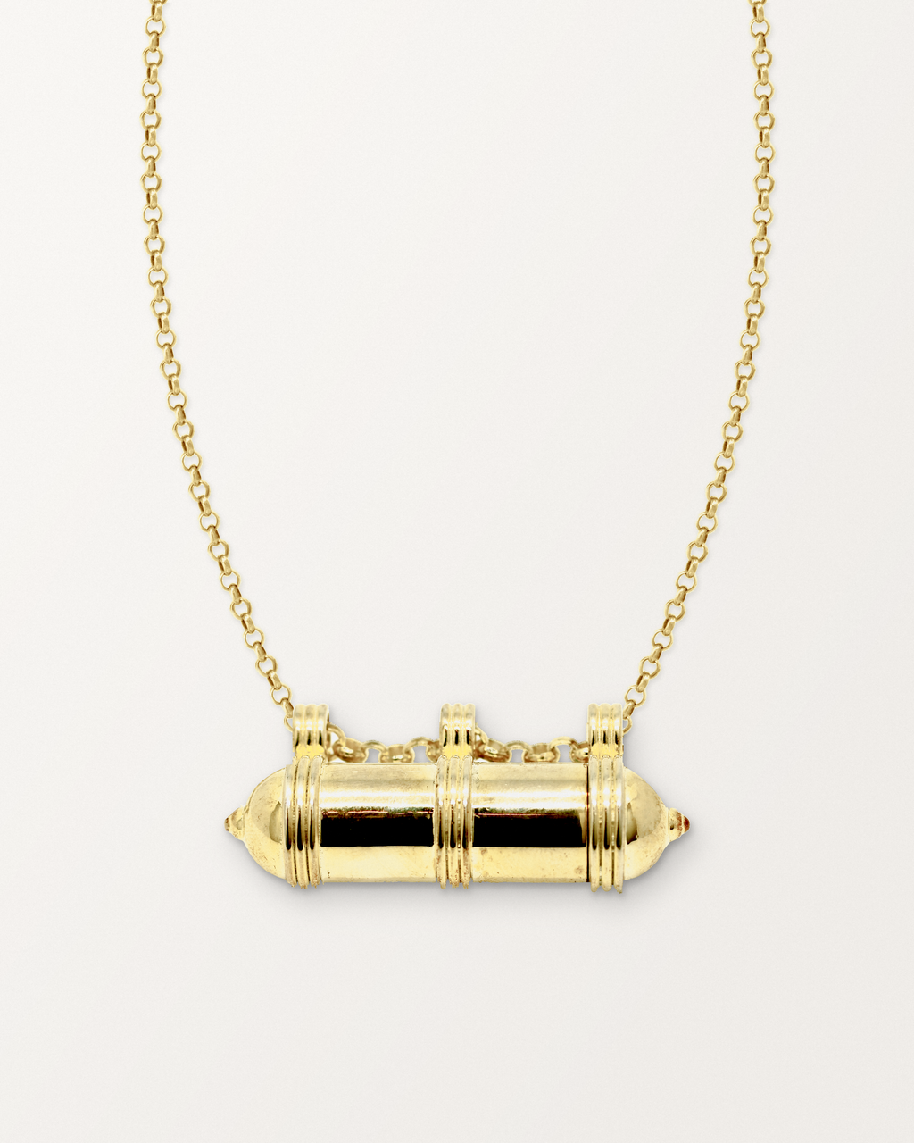Pankaj openable amulet necklace in 14K or 18K yellow gold, shown closed with its photographed details and matched chain on a warm bone-white background.