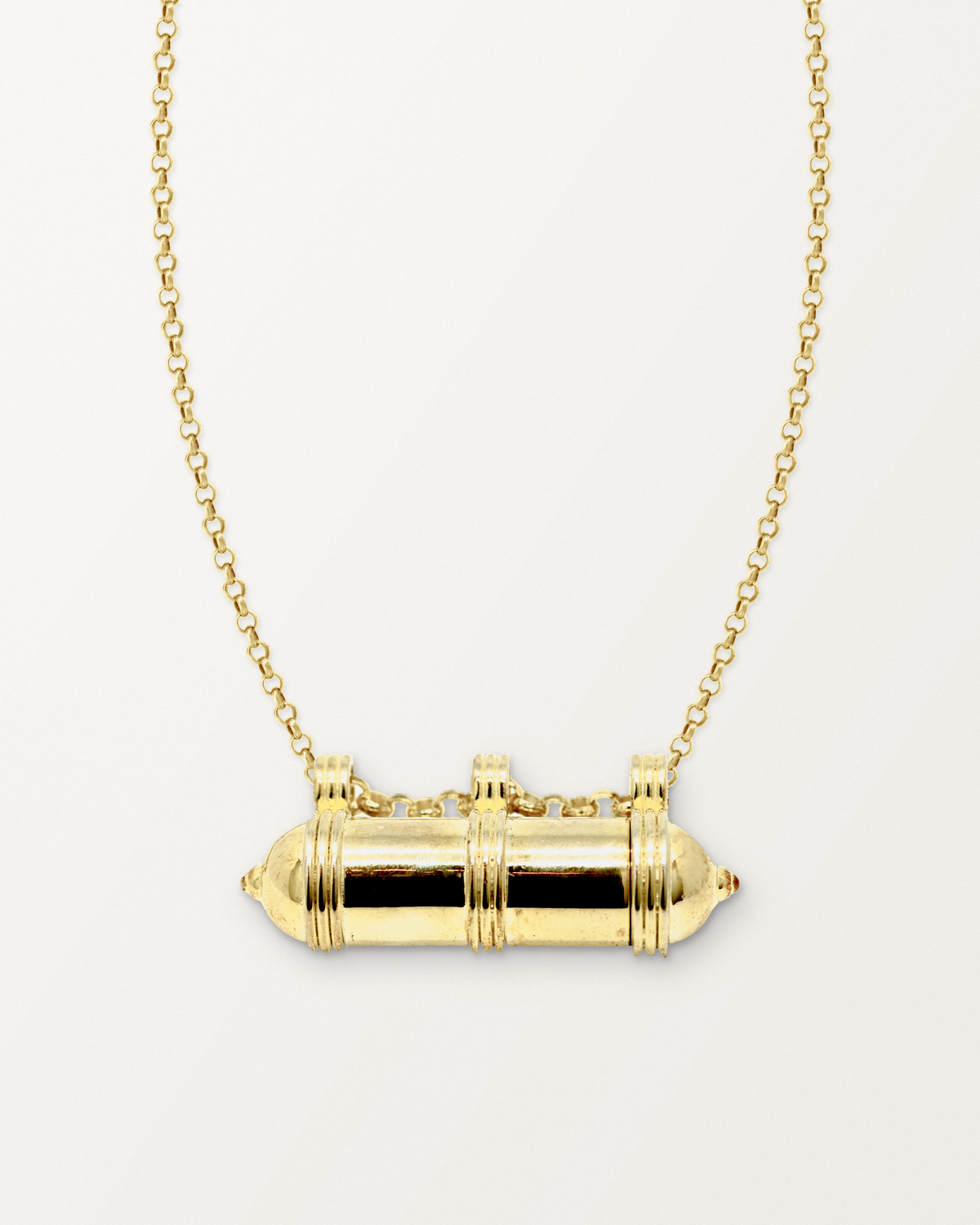 Pankaj openable amulet necklace in 14K or 18K yellow gold, shown closed with its photographed details and matched chain on a warm bone-white background.