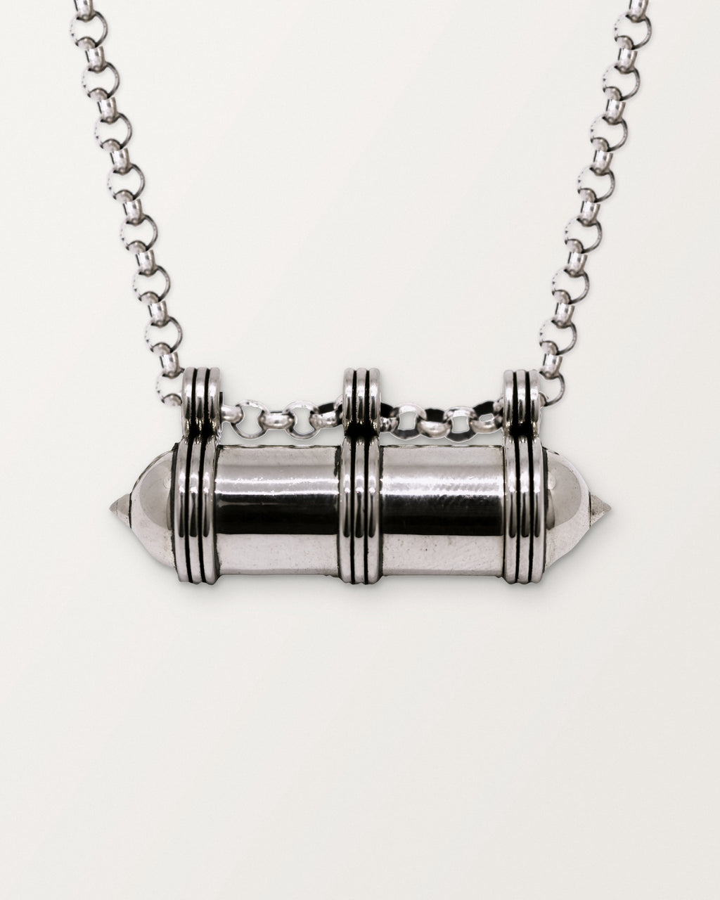 Close-up of the closed sterling silver Pankaj amulet necklace, front, on a warm bone-white background.