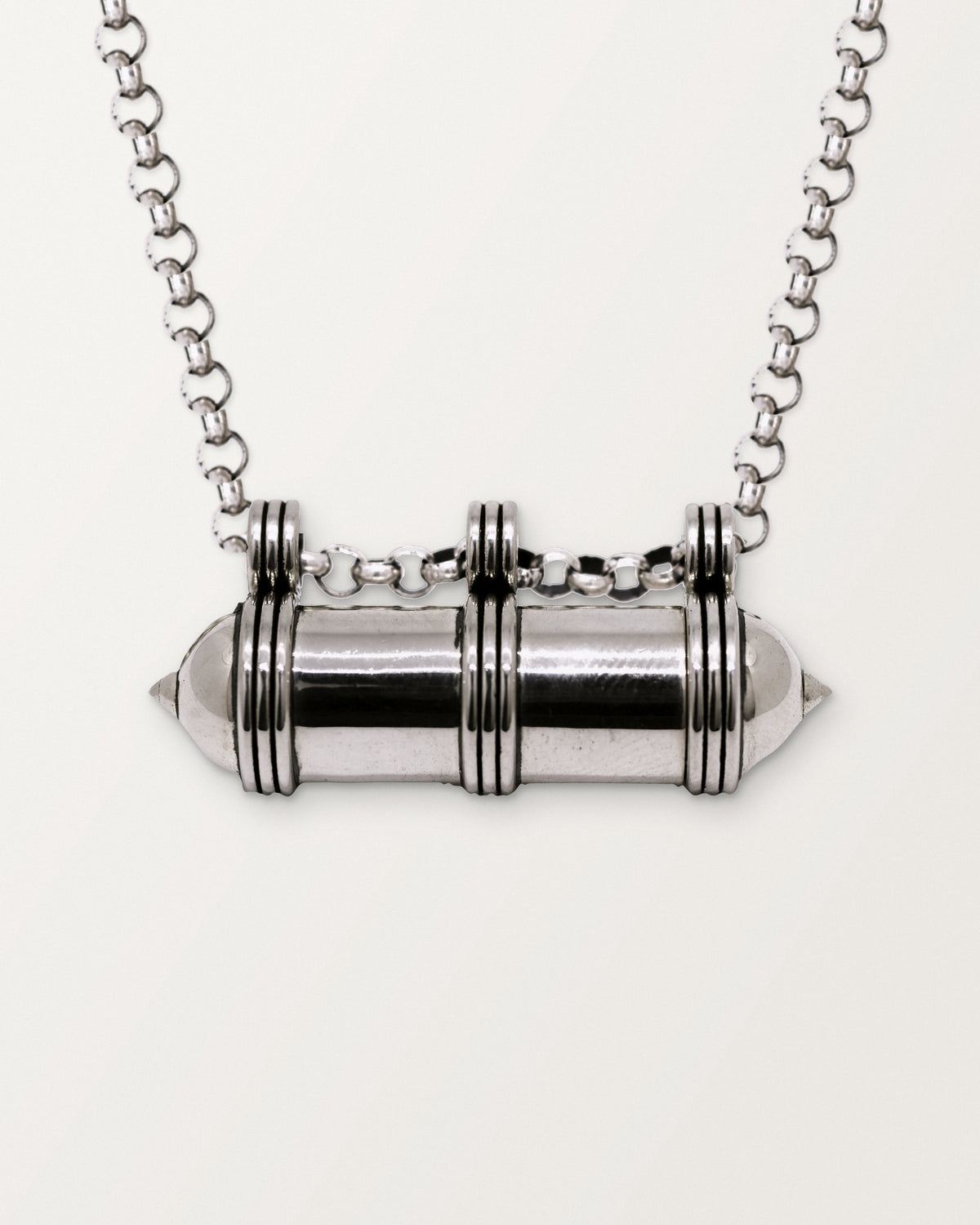 Close-up of the closed sterling silver Pankaj amulet necklace, front, on a warm bone-white background.