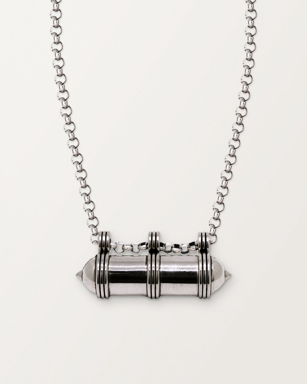 Sterling silver Pankaj amulet necklace, closed, on a warm bone-white background, chain exiting the top of frame.