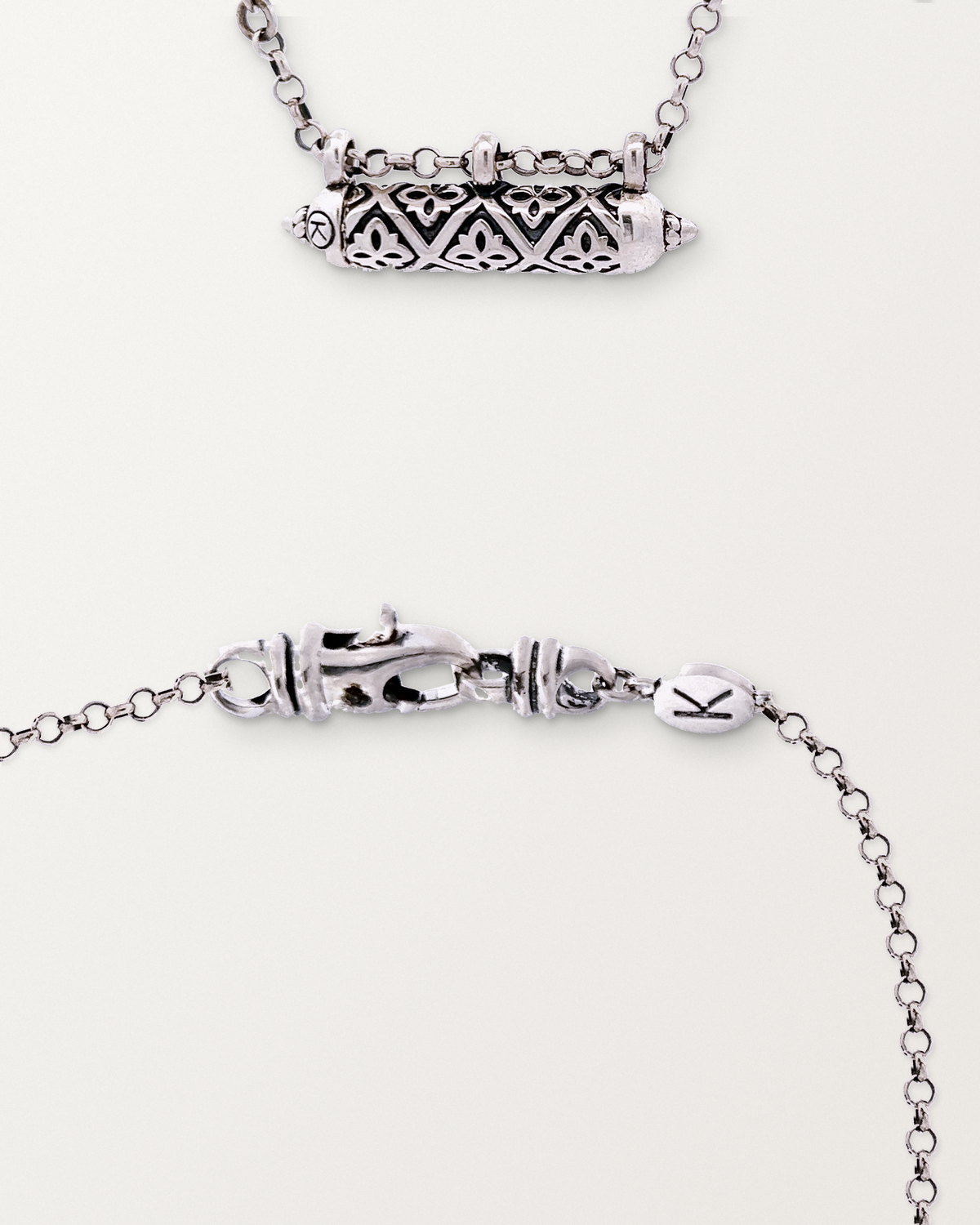 Sterling silver Shakti amulet beside a macro view of the lobster clasp and engraved oval K tag on its chain.