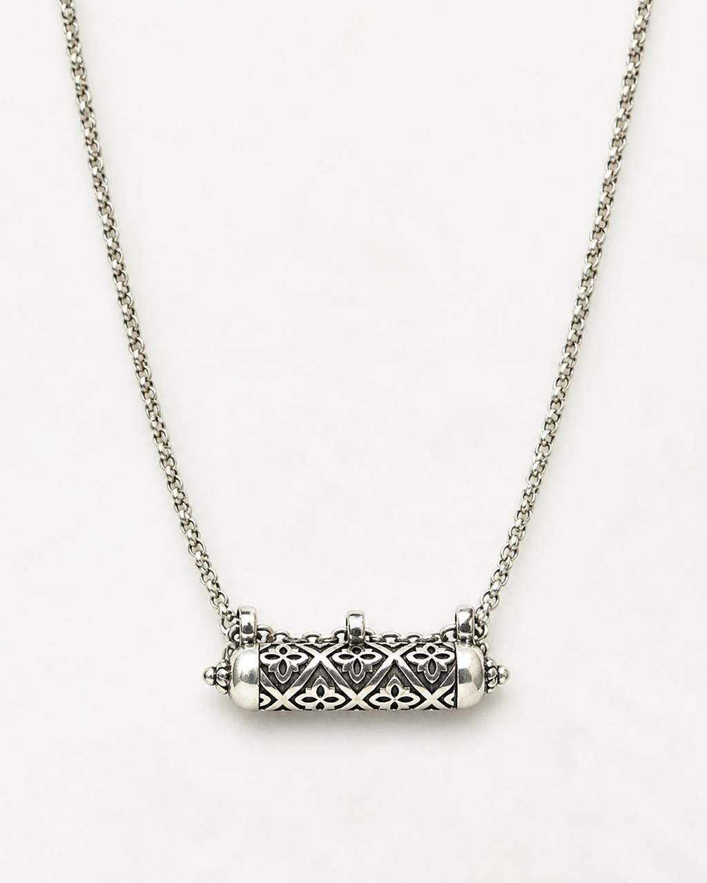 Shakti openable amulet necklace in sterling silver, shown closed on a warm bone-white background.