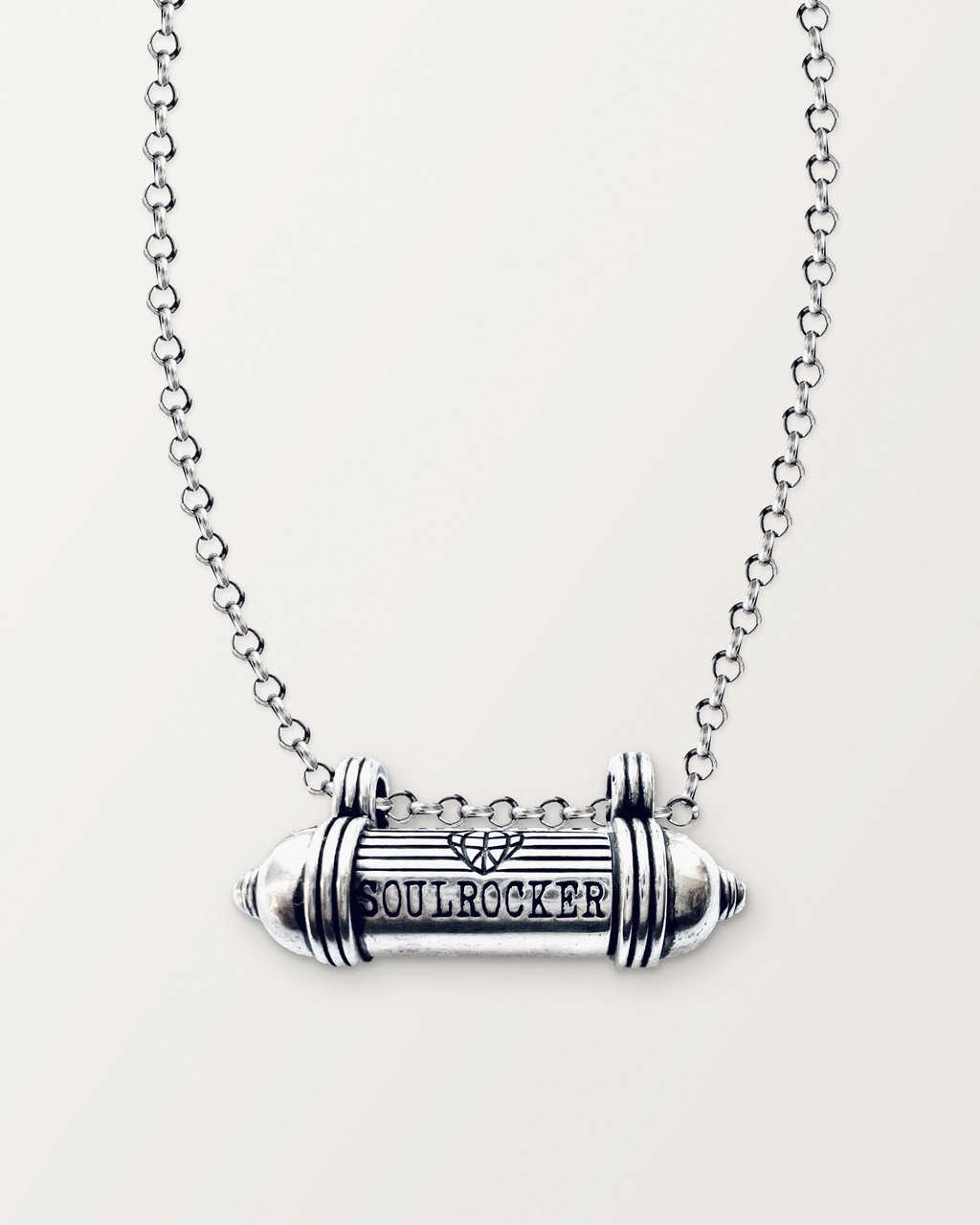 Sterling silver SOULROCKER amulet necklace, closed, engraved front, on its polished rolo chain against a warm bone-white background.