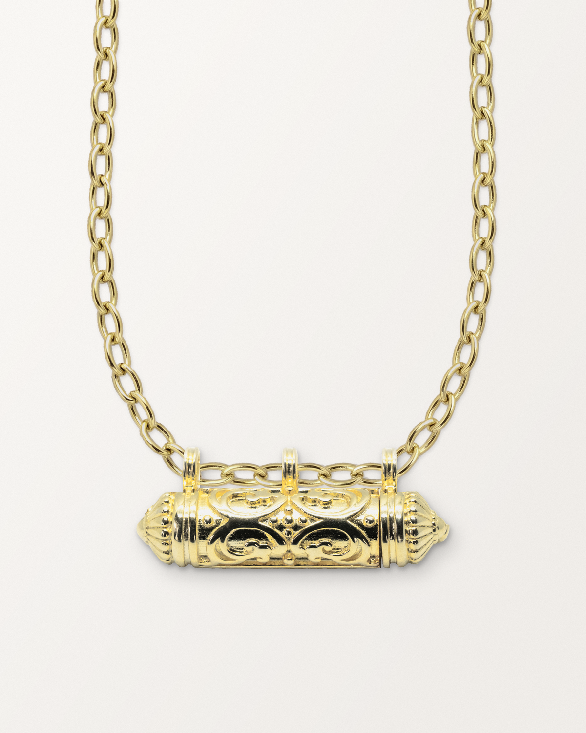 Sri openable amulet necklace in 14K or 18K yellow gold, shown closed on its chain on a warm bone-white background.