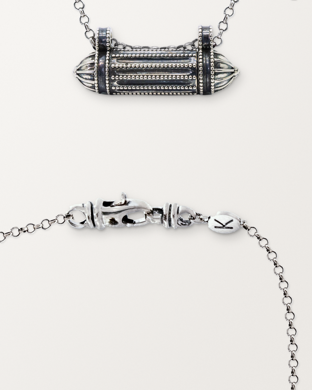 Sterling silver Taweez amulet beside a close view of the lobster clasp and oval K tag on its chain.
