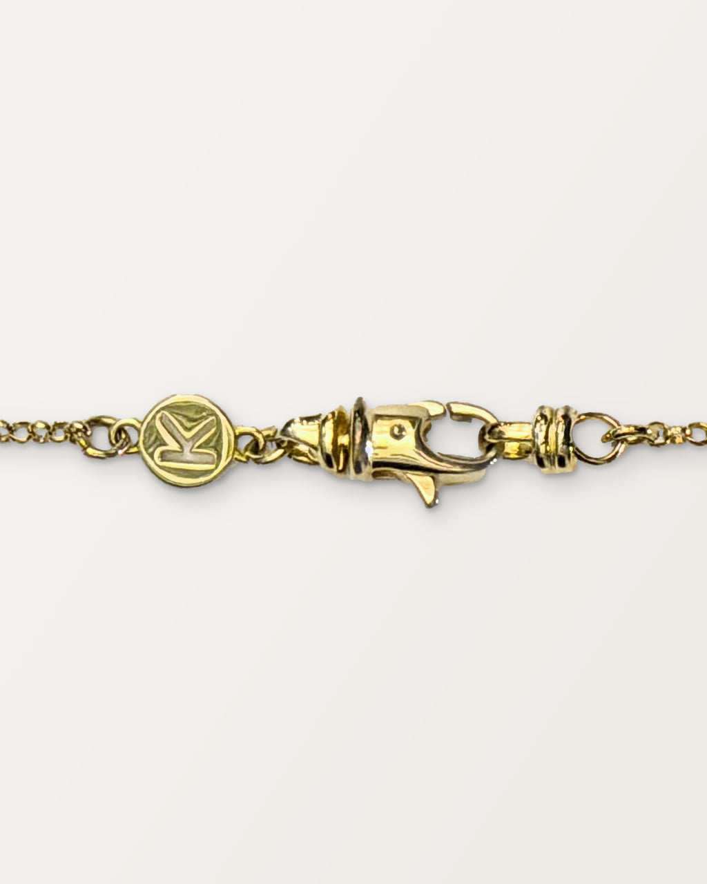 The small Kavacha clasp with its branded K tag, in 14K or 18K yellow gold.