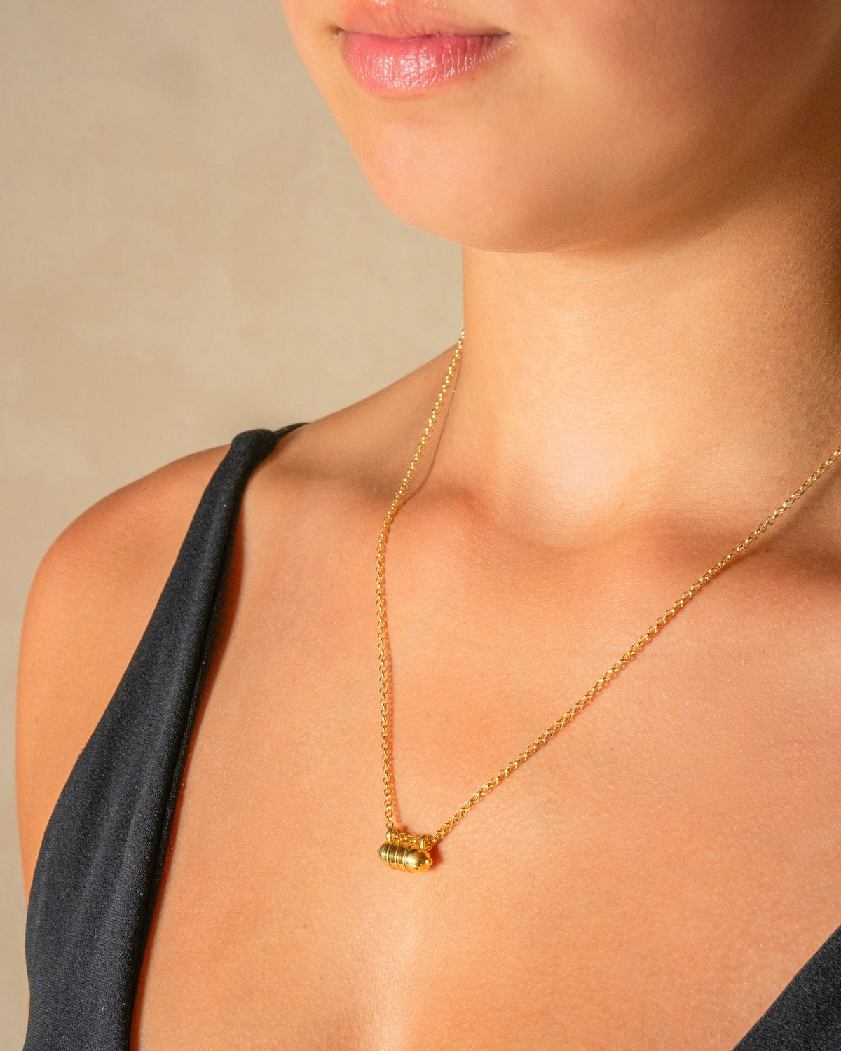 Vámana openable amulet necklace in 14K or 18K yellow gold, worn by a model.