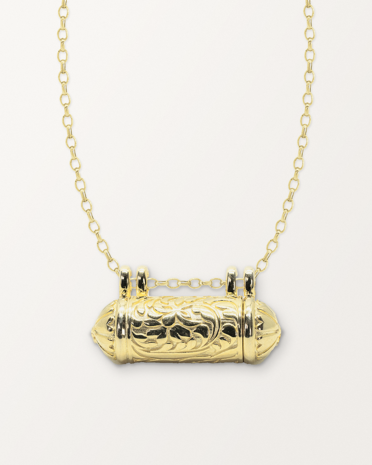 Vana openable amulet necklace in 14K or 18K yellow gold, closed, on a warm bone-white background.