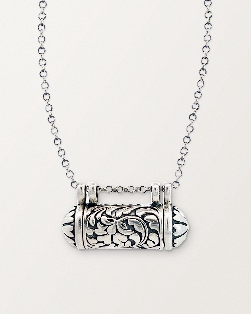 Sterling silver Vana amulet necklace, closed, on a warm bone-white background.