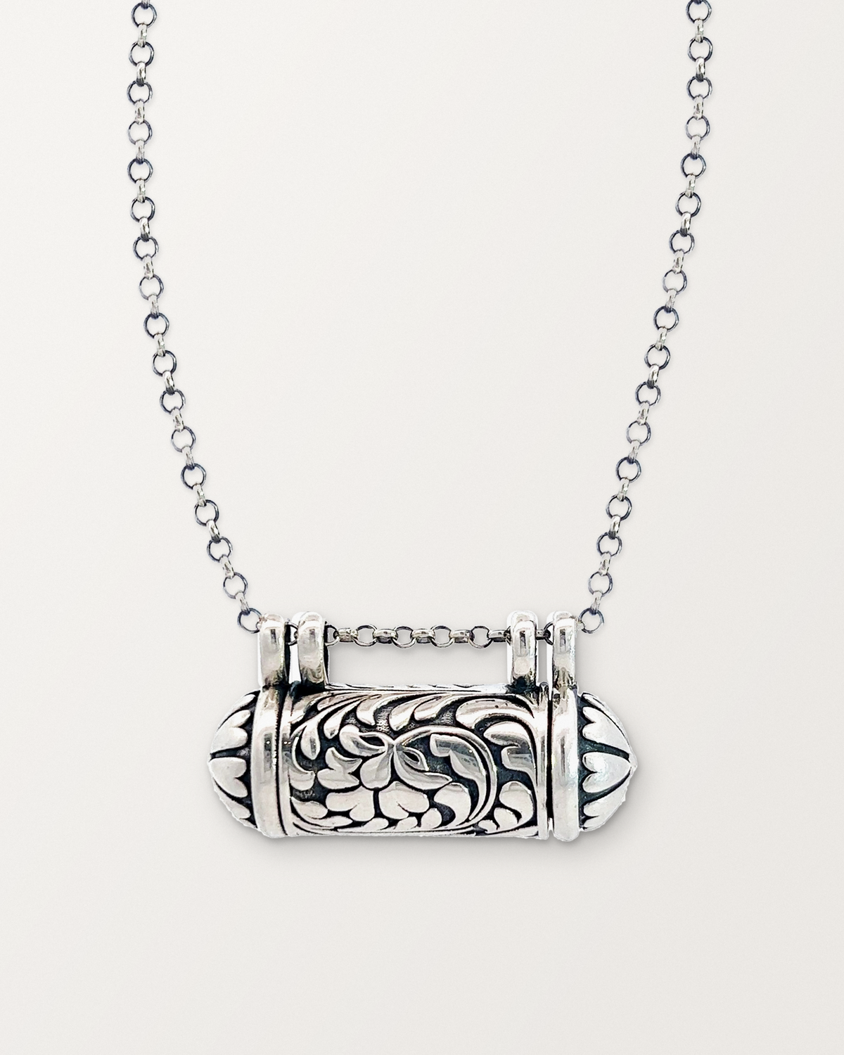 Sterling silver Vana amulet necklace, closed, on a warm bone-white background.