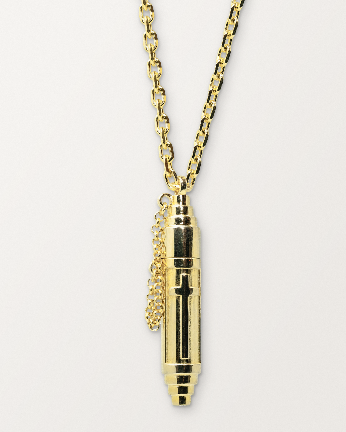 Vertical Cross openable amulet necklace in 14K or 18K yellow gold, shown closed on a warm bone-white background.