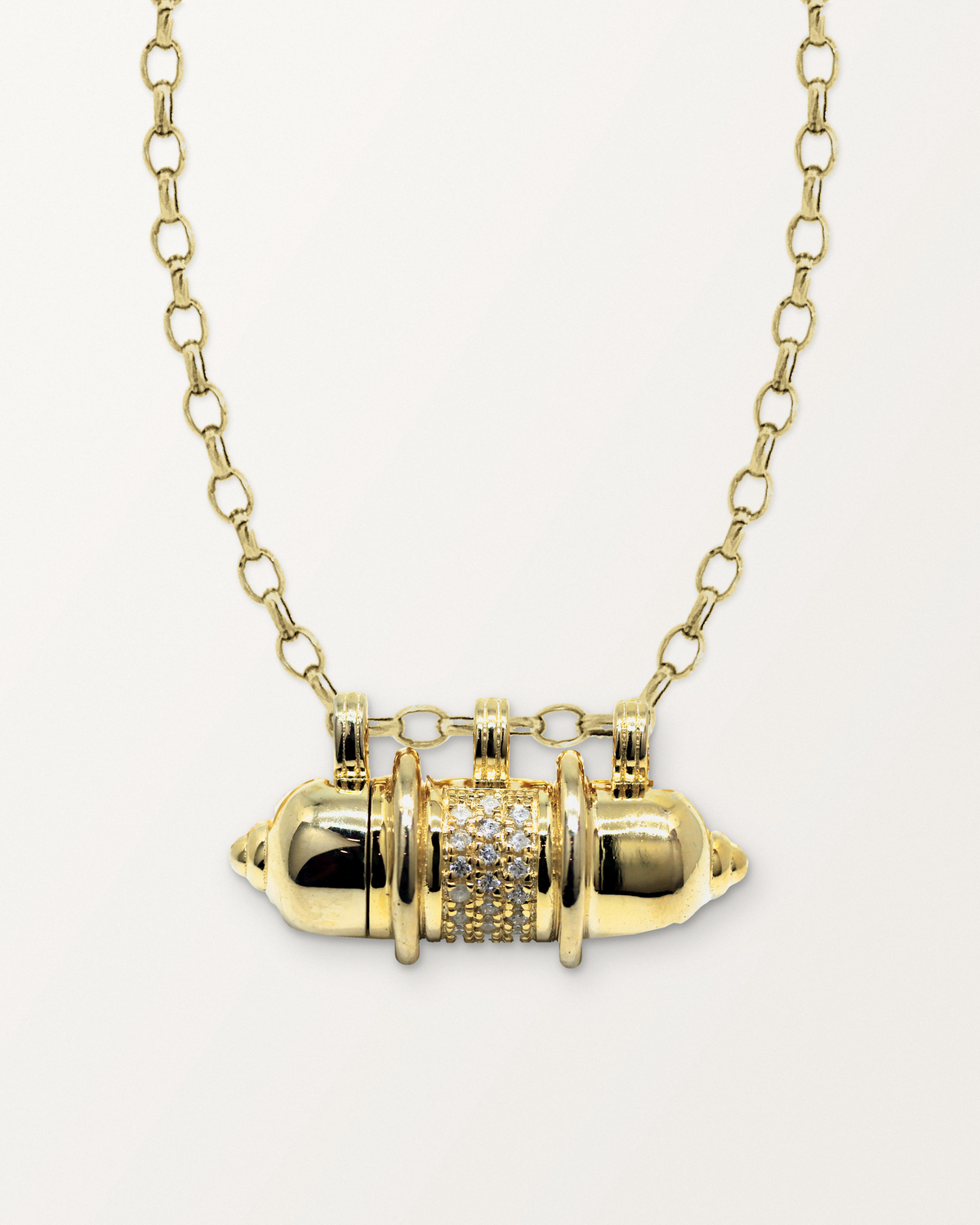 Vidya openable amulet necklace in 14K or 18K yellow gold, closed, on a warm bone-white background.