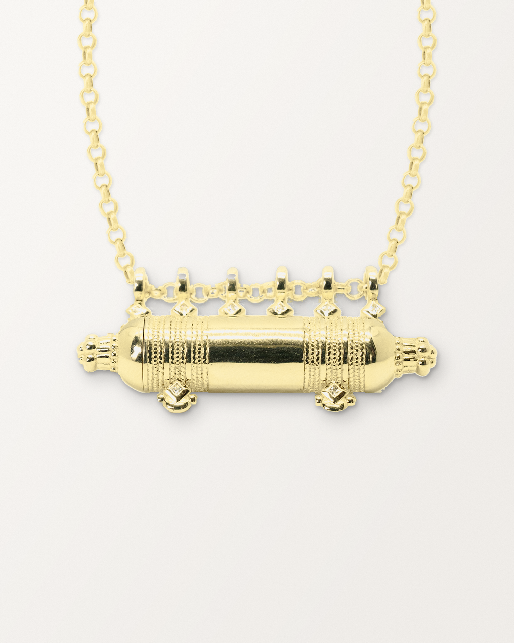Close-up of the Yemen Wedding openable amulet necklace in 14K or 18K yellow gold, closed, front, on a warm bone-white background.