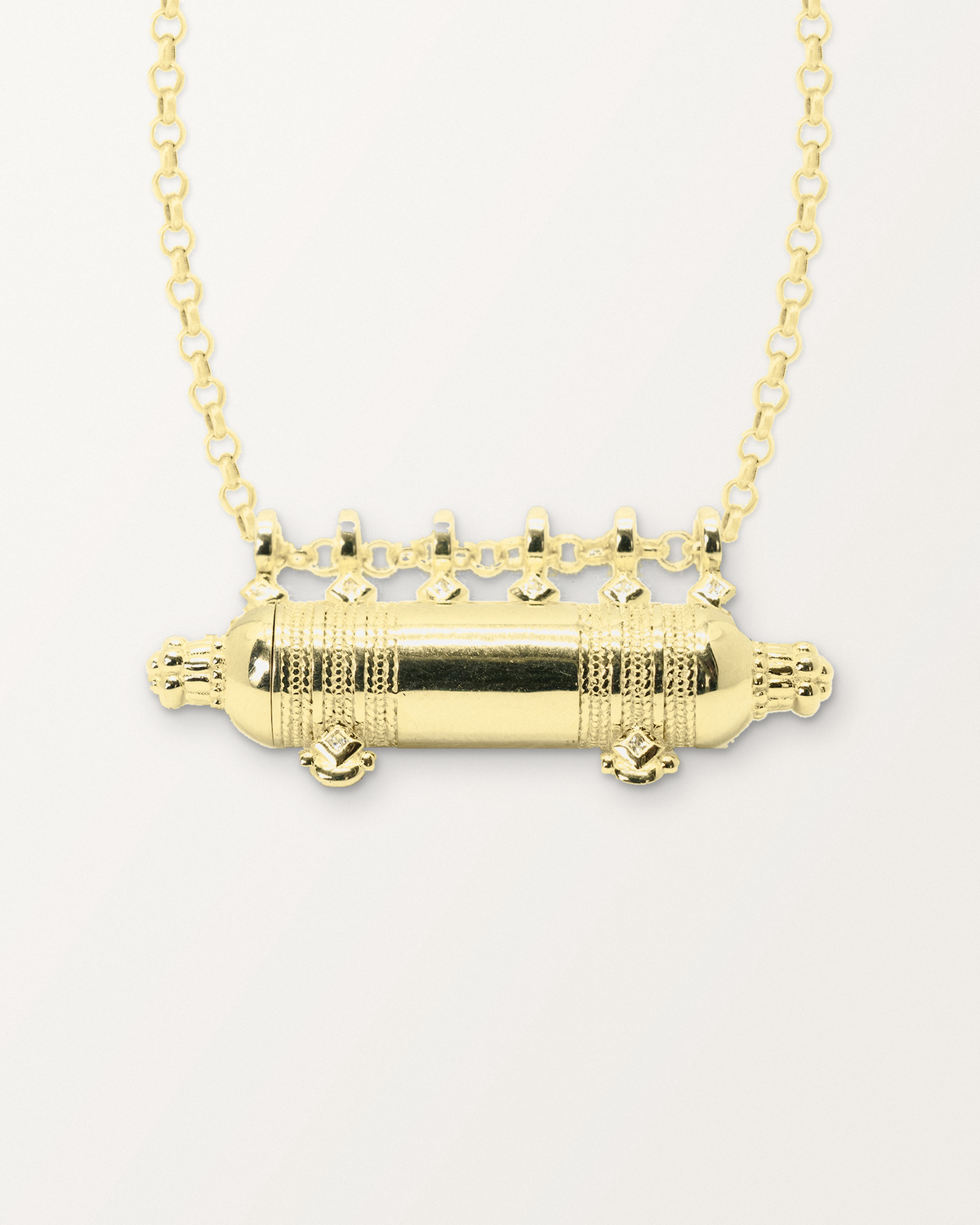 Close-up of the Yemen Wedding openable amulet necklace in 14K or 18K yellow gold, closed, front, on a warm bone-white background.