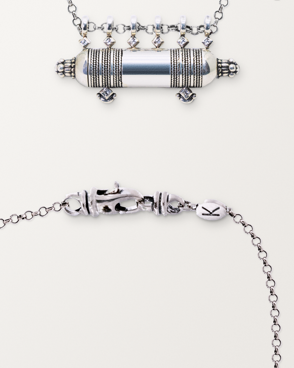 Sterling silver Yemen Wedding amulet beside a close view of the lobster clasp and oval K tag on its chain.