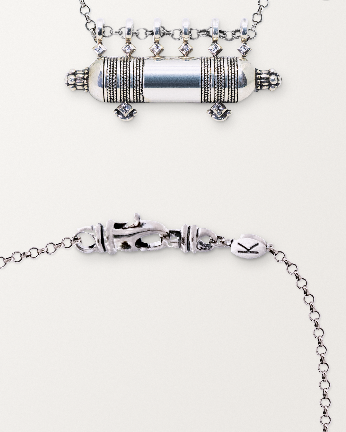 Sterling silver Yemen Wedding amulet beside a close view of the lobster clasp and oval K tag on its chain.