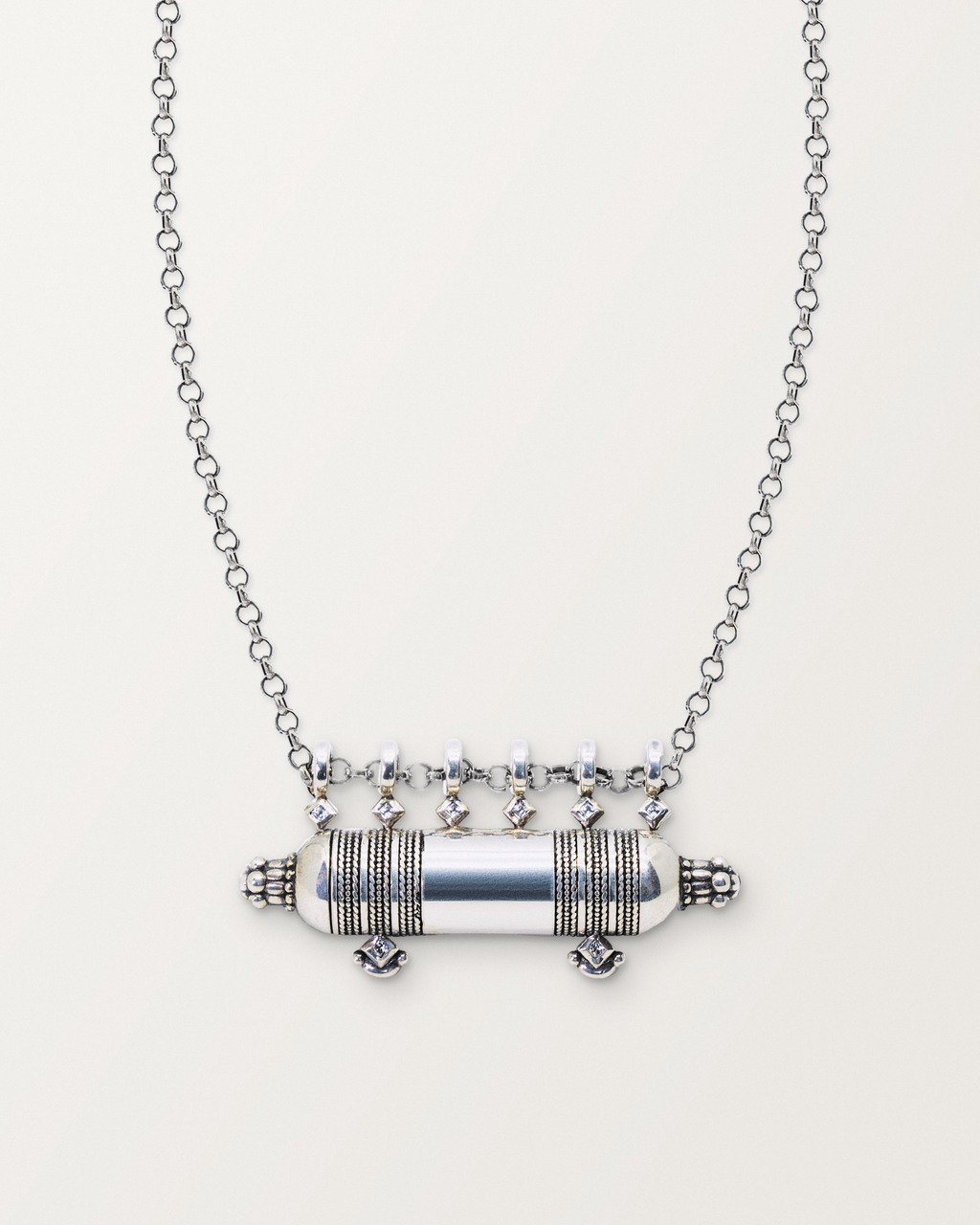 Sterling silver Yemen Wedding amulet necklace, closed, on a warm bone-white background, chain exiting the top of frame.